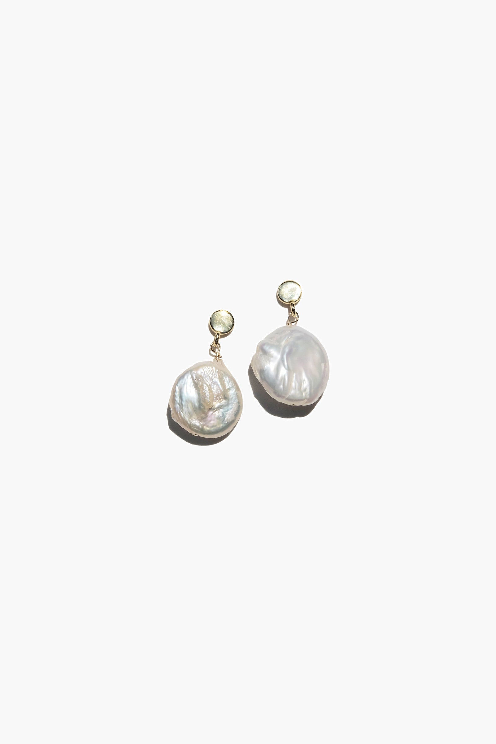 A pair of Playa earrings featuring coin-shaped keshi baroque pearls in silver and gold vermeil finishes.