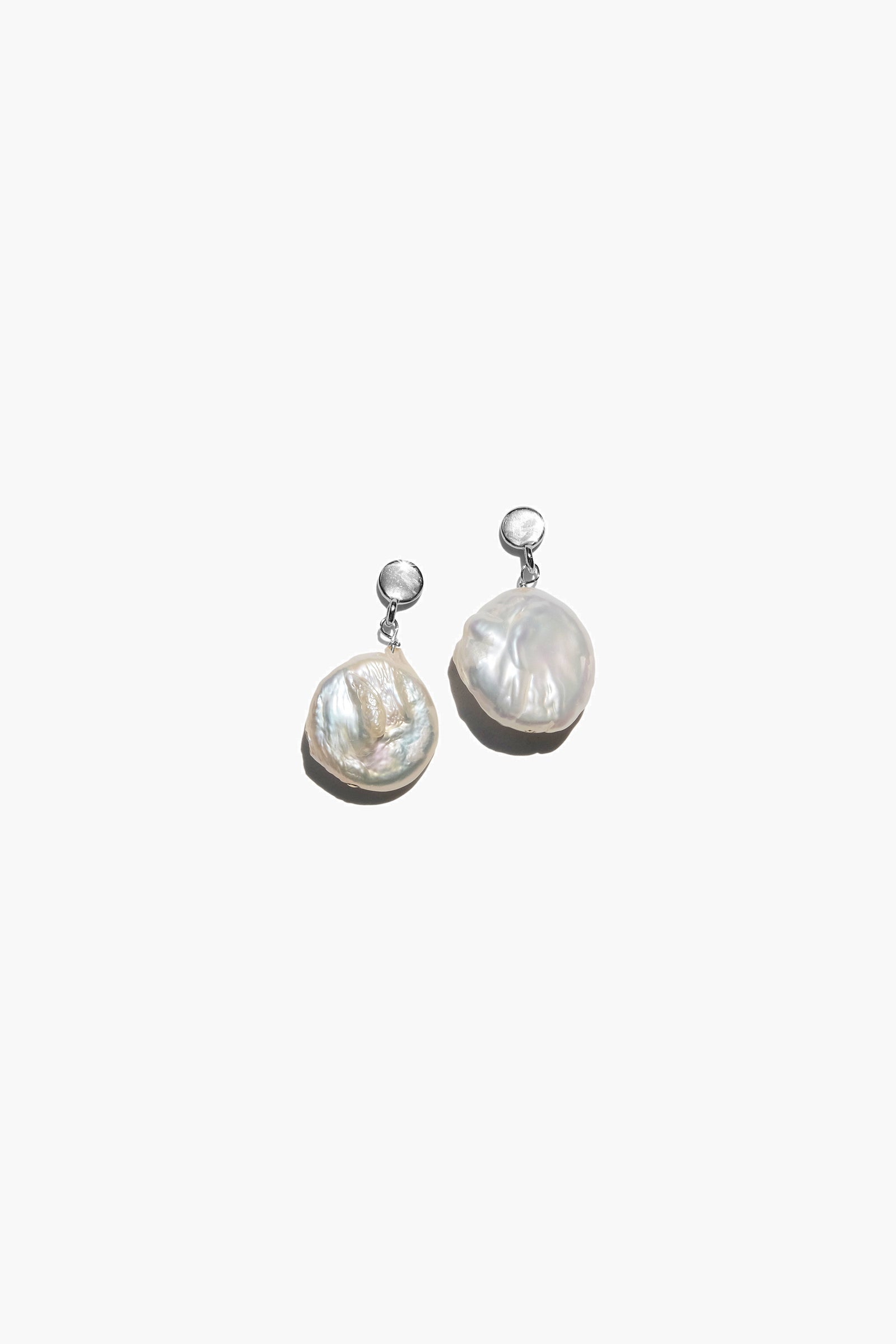 A pair of Playa earrings featuring coin-shaped keshi baroque pearls in silver and gold vermeil finishes.